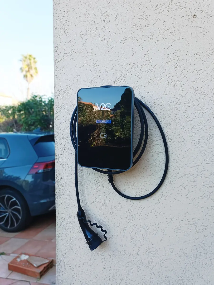 Borne de recharge V2C avec câble attaché installée à proximité du véhicule et de sa place de stationnement