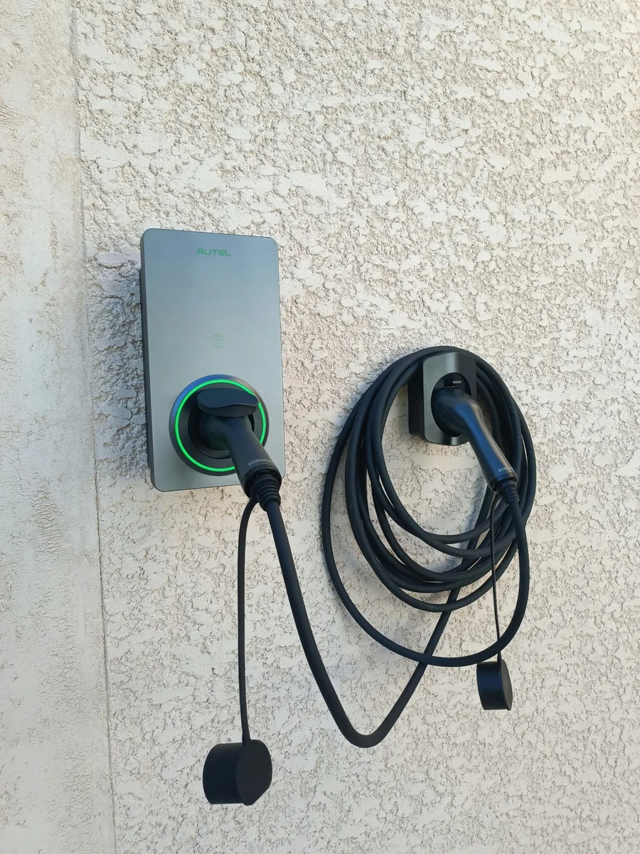 Borne Autel installée par SYSUR sur une façade extérieure avec son câble de recharge rangé sur un support mural
