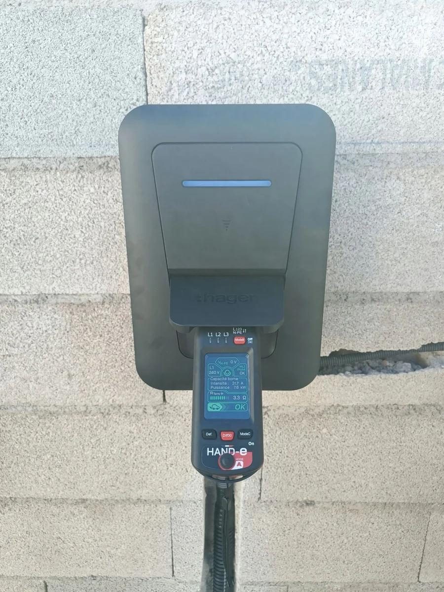 Contrôle d’une borne de recharge Hager avec un testeur HAND-e branché sur la prise, lors d’une intervention SYSUR