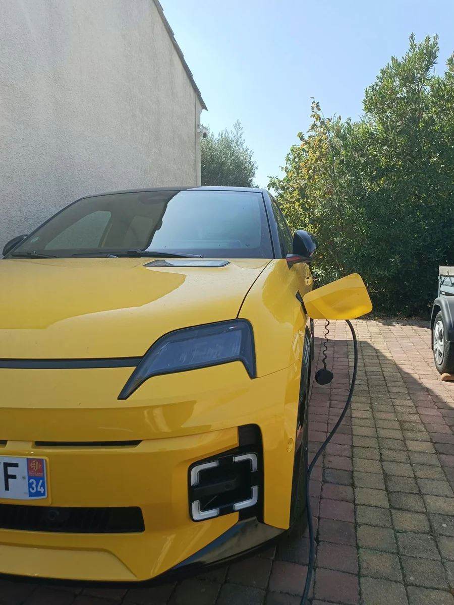 Véhicule électrique jaune branché à domicile dans une allée, lors d’une réalisation IRVE SYSUR
